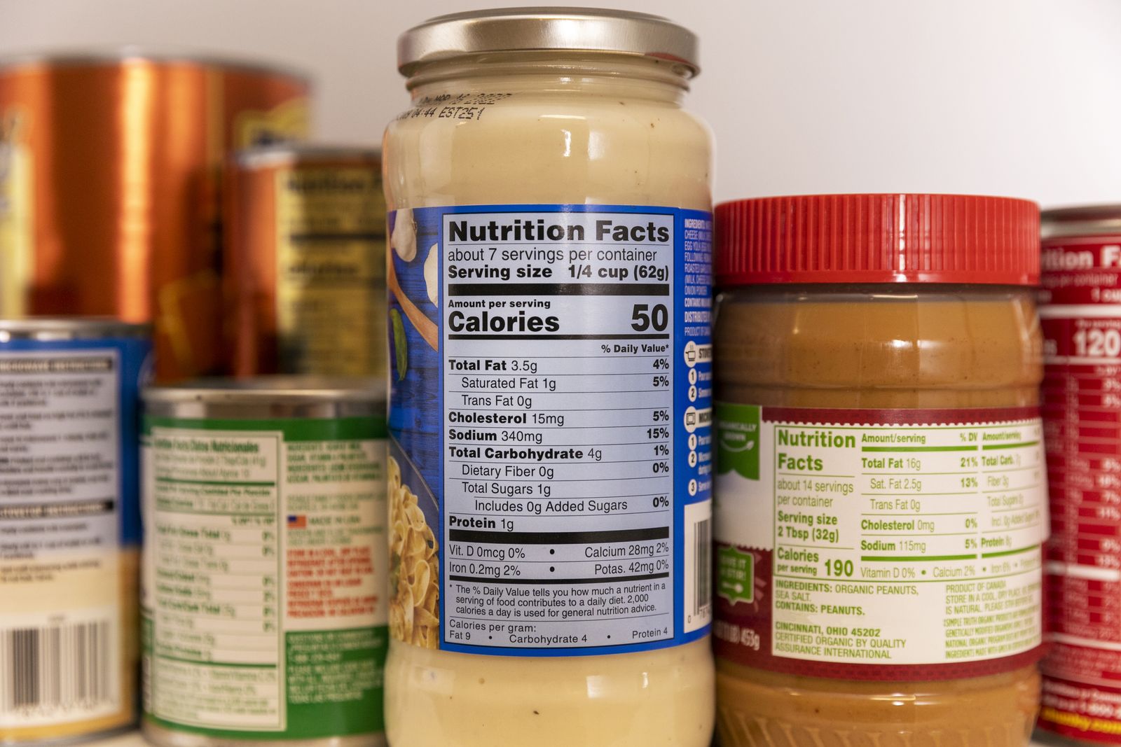 Jars and cans in a pantry turned to show their Nutrition Facts labels, with serving size and calories